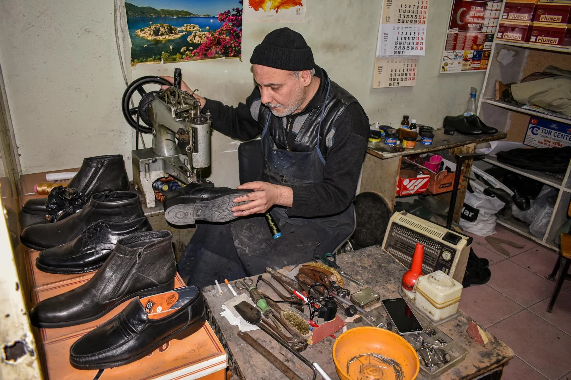 Master cobbler repairing shoes with sewing machine at workbench in traditional workshop