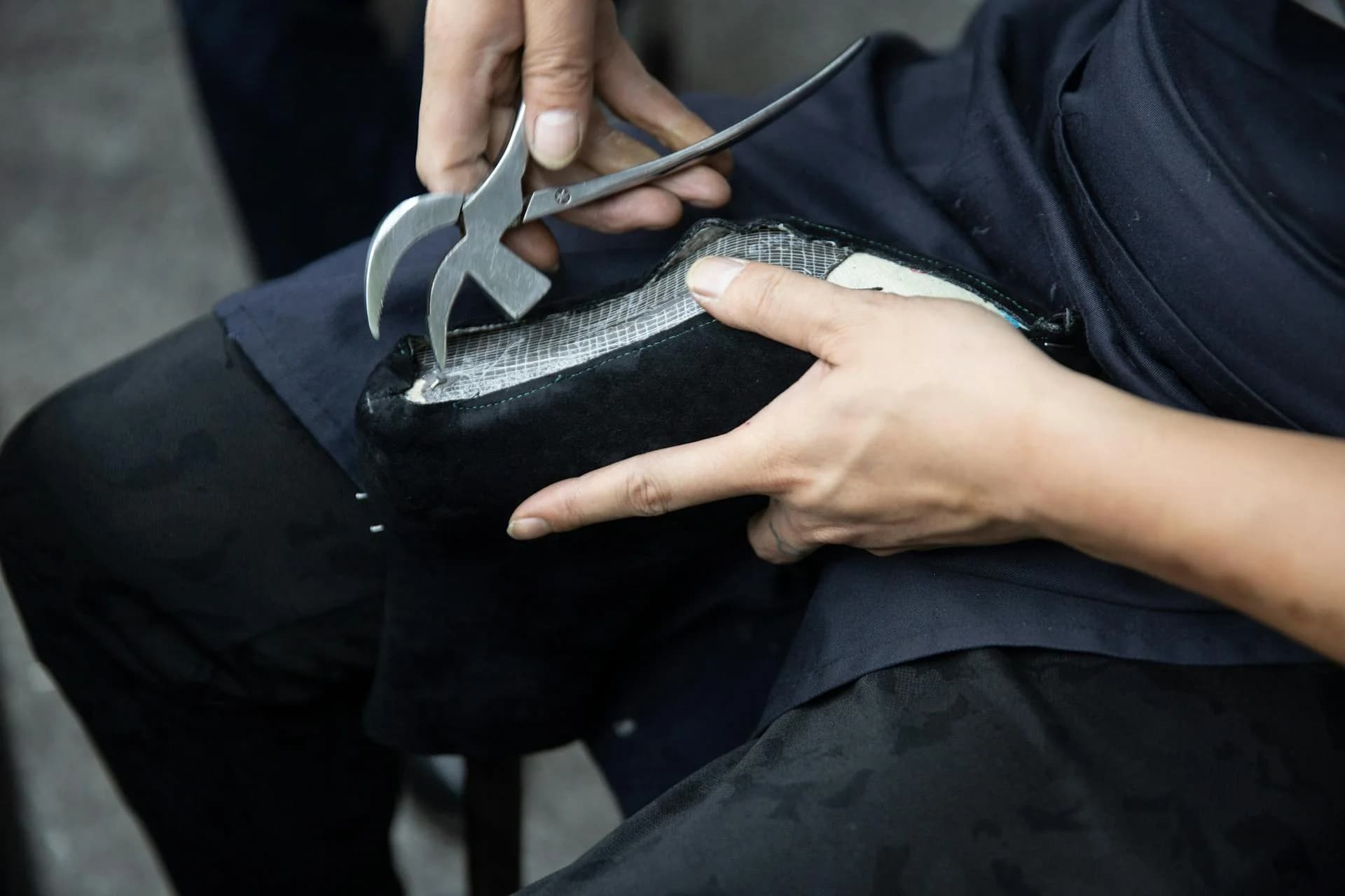 Expert cobbler repairing a leather shoe with lasting pliers in a professional workshop