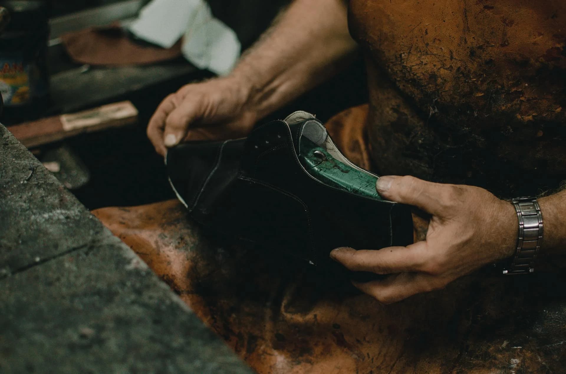 Artisan cobbler holding a leather shoe on a last in workshop