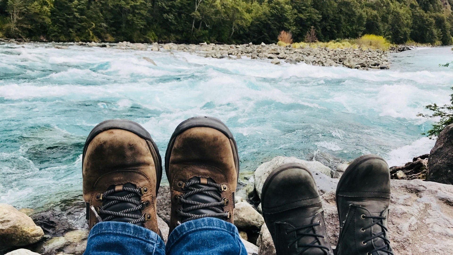 Bottes de randonnée posées sur des rochers surplombant une rivière de montagne — service de réparation de bottes de plein air au Canada