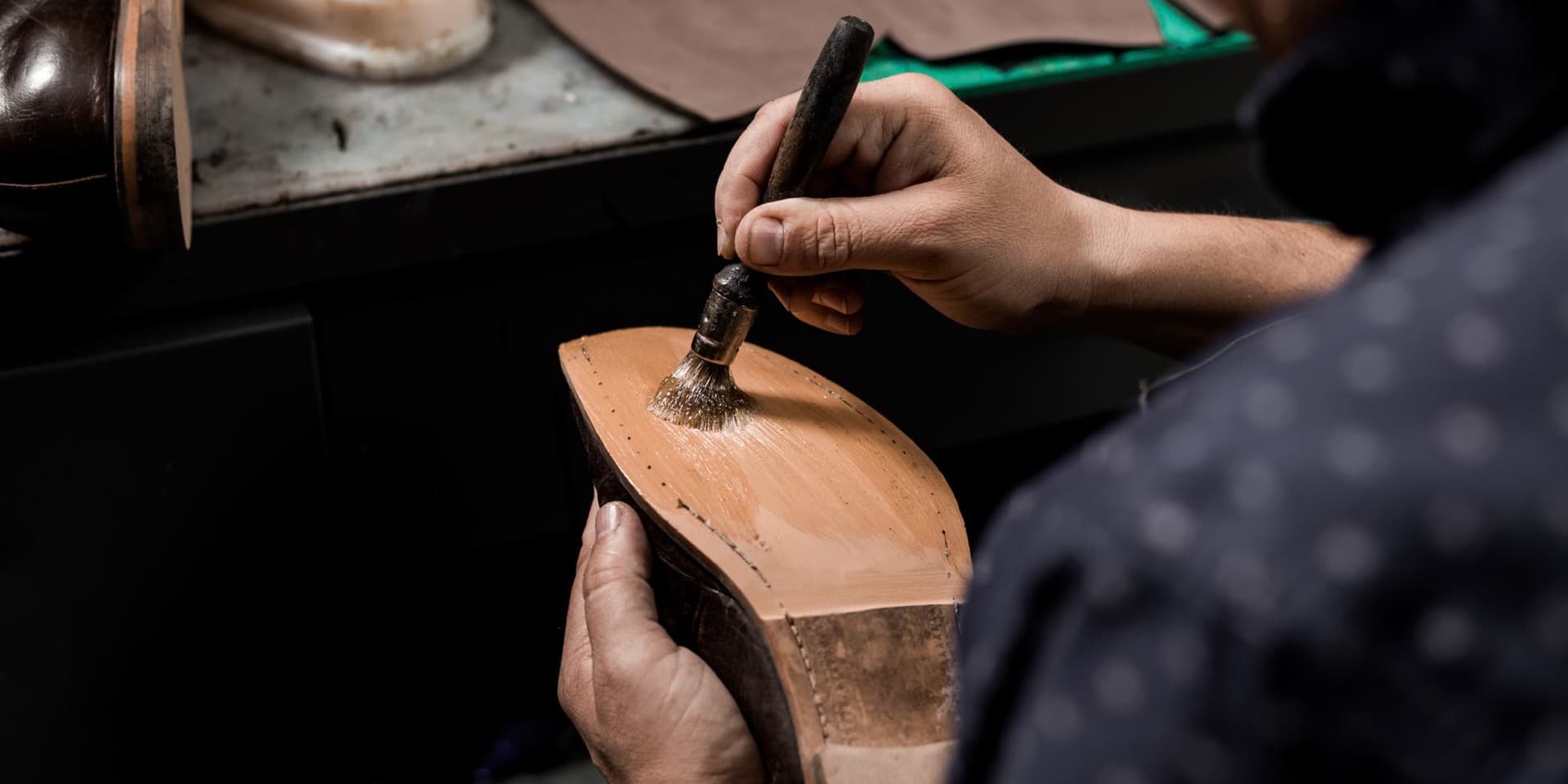 Cordonnier canadien appliquant de la colle sur une semelle en cuir lors d'un ressemelage professionnel en atelier