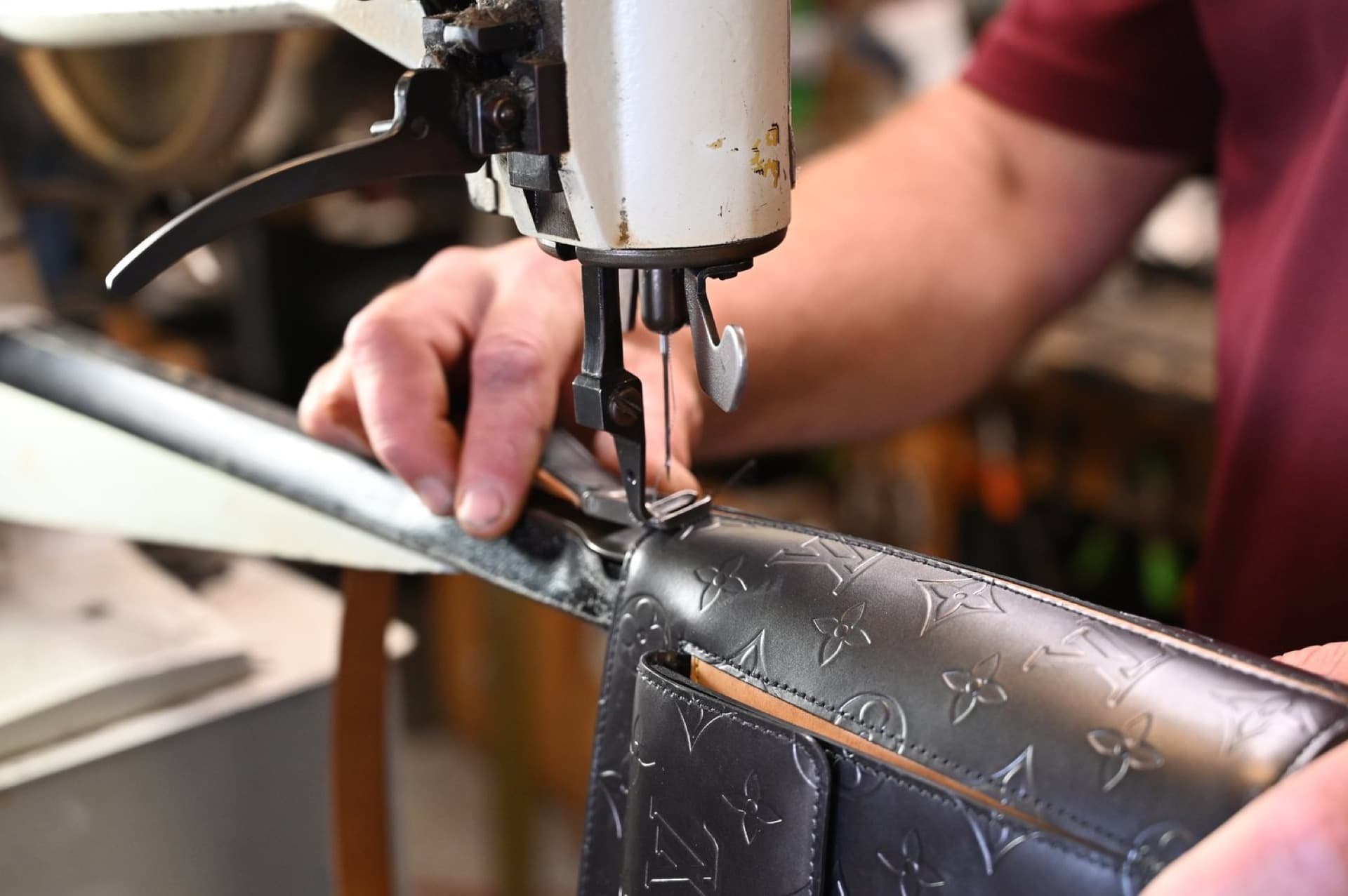 Cordonnier cousant la bandoulière d'un sac à main en cuir de designer sur machine à coudre industrielle — service professionnel de réparation de sacs au Canada