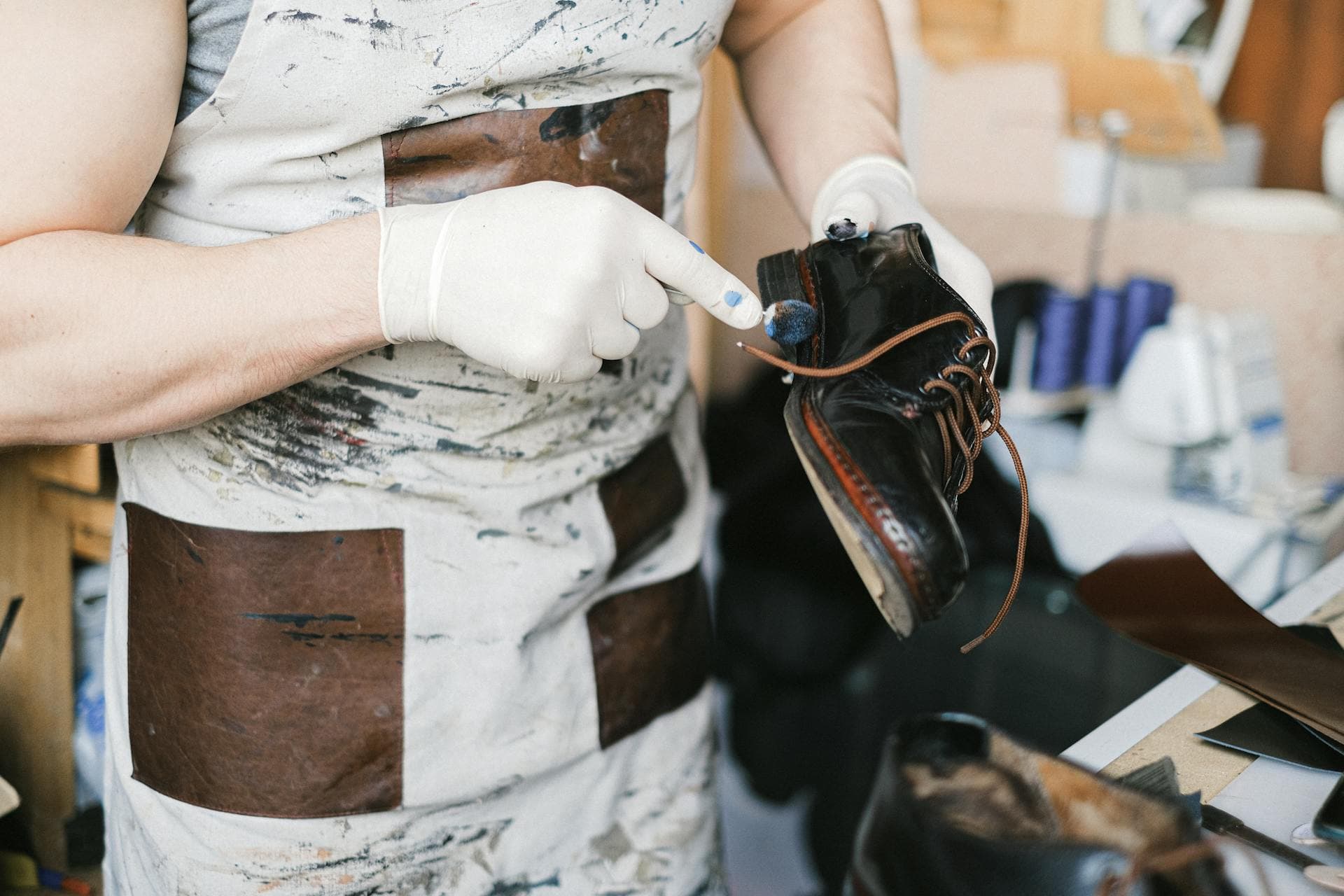 Artisan appliquant de la teinture et du fini sur une chaussure en cuir noir avec des gants